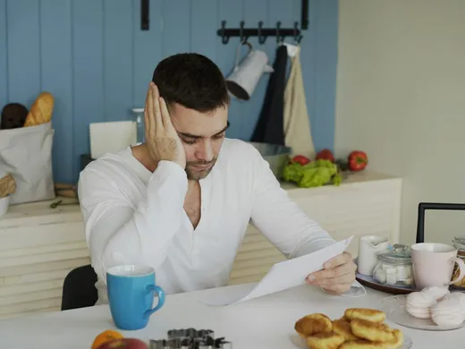 Reading an unpaid bill at the kitchen table